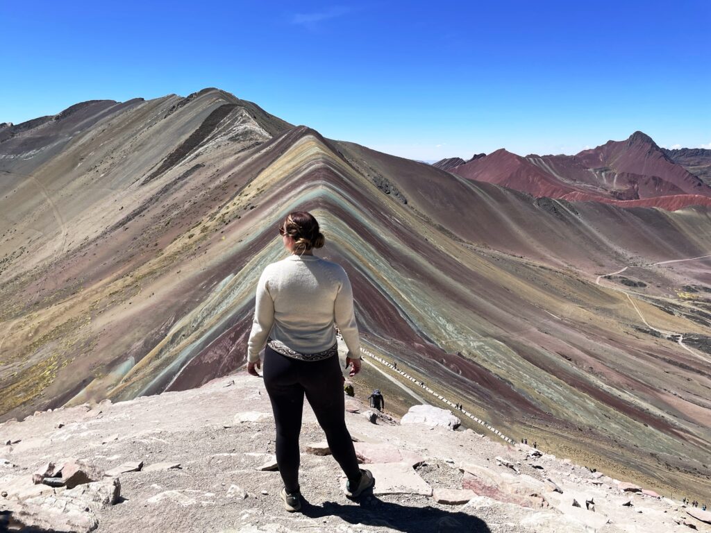 Image of author Elizabeth Frame facing away from the camera looking at Rainbow Mountain in Peru.
